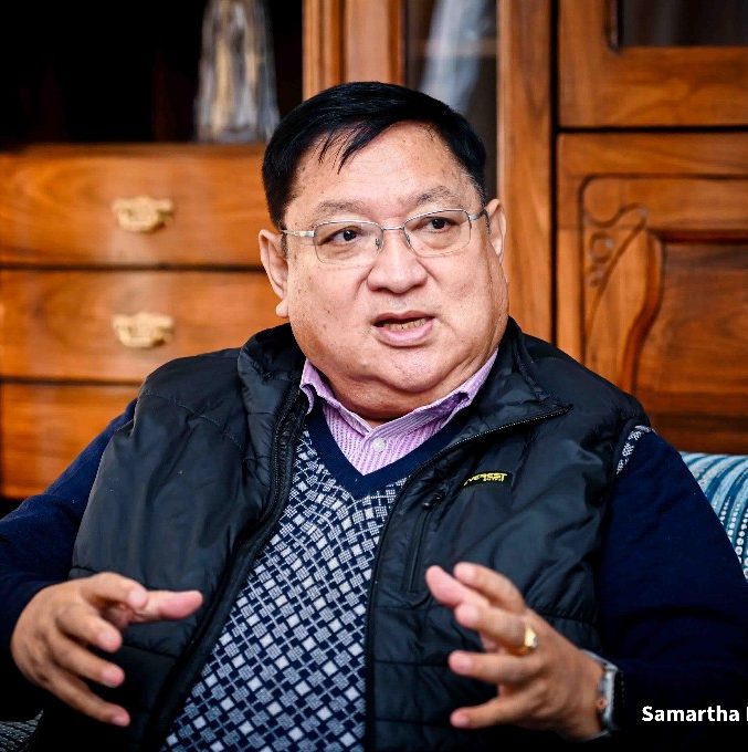 Portrait of Mr. Umesh Shrestha in formal attire smiling confidently with Nepalese flag background